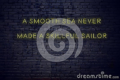 Positive inspiring quote on neon sign against brick wall a smooth sea never made a skillful sailor Stock Photo