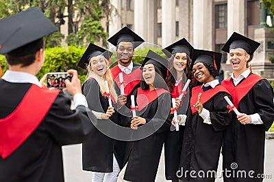 Positive international students celebrating graduation, taking photos Stock Photo