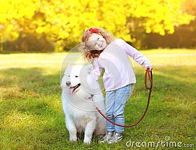 Positive little girl and dog having fun outdoors Stock Photo