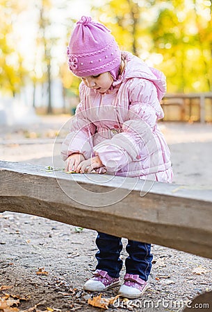 Positive little girl playing in the autumn park. Happy emotional child catches maple leaves. active holiday in autumn. leaf fall Stock Photo