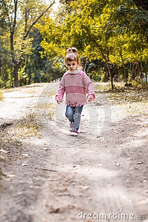 Positive little girl playing in the autumn park. Happy emotional child catches maple leaves. active holiday in autumn. leaf fall Stock Photo