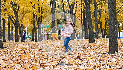 Positive little girl playing in the autumn park. Happy emotional child catches maple leaves and laughs. active holiday in autumn. Stock Photo