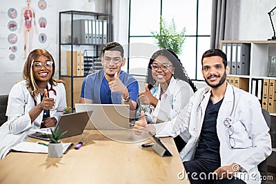 Multiracial doctors showing thumbs up at office meeting Stock Photo