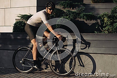 Positive man biking on street during summer time Stock Photo
