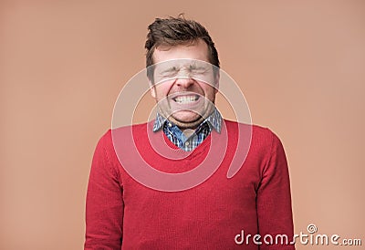 Guy grins at camera, shows white teeth, closes eyeswaiting for gift Stock Photo