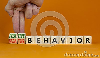 Positive or negative behavior symbol. Businessman turns cubes, changes words negative behavior to positive behavior. Orange Stock Photo