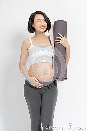 Positive pregnant woman in sports clothes holds a gym Mat in her hands Stock Photo