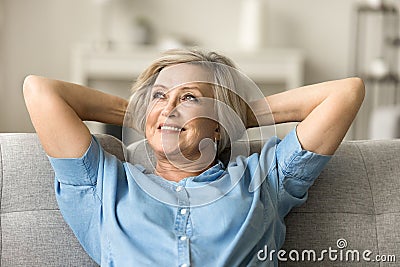 Positive pretty elderly mature woman relaxing on home couch Stock Photo