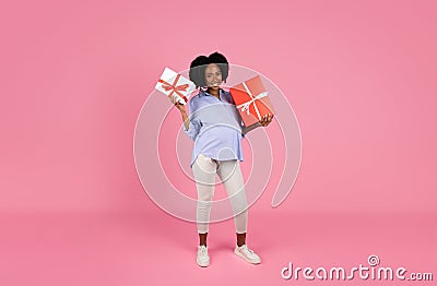Positive pretty young black pregnant lady in casual with big belly shows boxes with gifts on gender party Stock Photo
