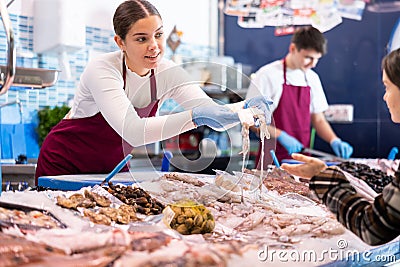 Positive saleswoman demonstrating calamary in fish store Stock Photo