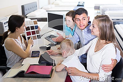 Saleswoman in furniture store helping young family in choice of mattress material Stock Photo