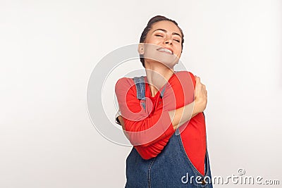 Positive self-esteem. Portrait of stylish girl embracing herself and smiling with expression of pleasure, being selfish Stock Photo