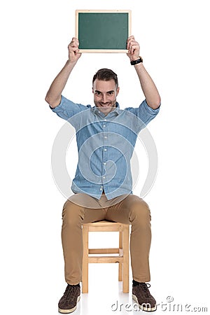 Positive smart casual man holding blackboard above his head, smiling Stock Photo