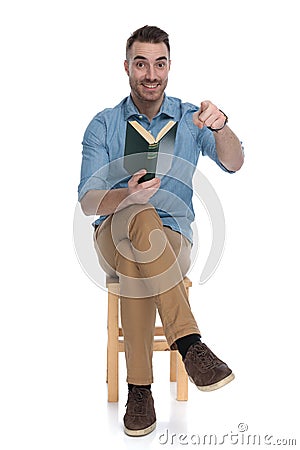 Positive smart casual man holding book and pointing, smiling Stock Photo