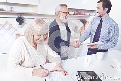 Positive smilign aged woman signing insurance contract Stock Photo