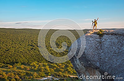 Positive smiling photographer with tripod on the rock in the eve Stock Photo