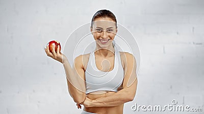 Positive sportswoman holding apple and looking Stock Photo