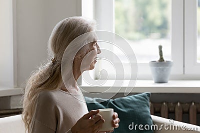 Positive thoughtful mature blonde lady enjoying coffee break Stock Photo