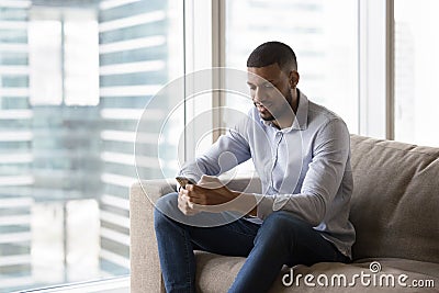 Positive thoughtful young African business man using mobile phone Stock Photo