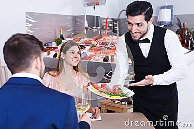 Positive waiter serving seafood meals to guests Stock Photo