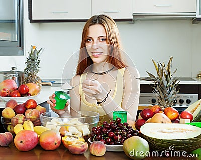 Positive woman making fruit salad with yoghourt Stock Photo