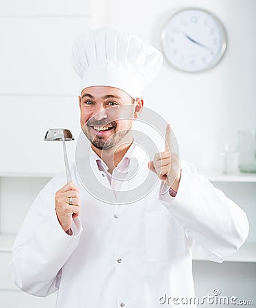 Positive young cook holding soup ladle Stock Photo