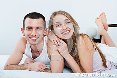 Positive young happy adults lying in family bed Stock Photo