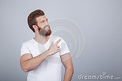 Positive young male freelancer or blogger being satisfied with results of work, has friendly pleasant smile, points upwards with Stock Photo