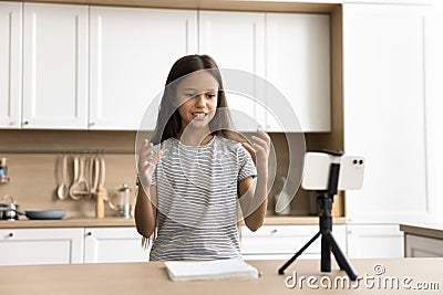 Positive young schoolkid pre teen blogger girl speaking at smartphone Stock Photo