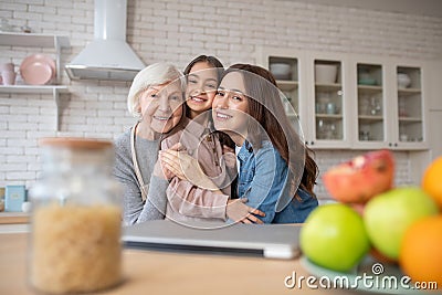 Young woman,elderly woman and little girl embraced smiling. Stock Photo