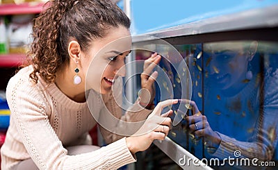 Positive young woman selecting aquarium fish Stock Photo