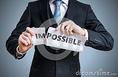 Possibility concept. Man is tearing paper with impossible word Stock Photo