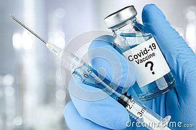 Possible cure with a hand in blue medical gloves holding Coronavirus, Covid 19 virus, vaccine vial Stock Photo