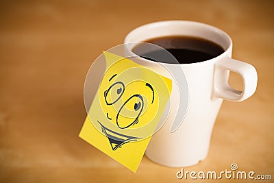 Post-it note with smiley face sticked on cup Stock Photo