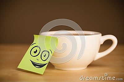 Post-it note with smiley face sticked on cup Stock Photo