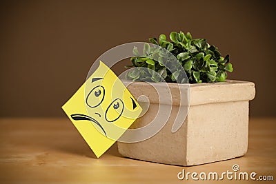 Post-it note with smiley face sticked on flowerpot Stock Photo