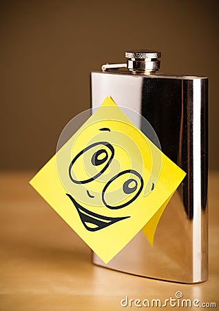 Post-it note with smiley face sticked on hip flask Stock Photo