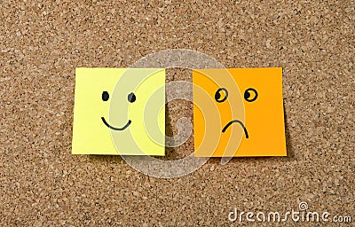 Post it notes on corkboard with smiley and sad cartoon face expression in happiness versus depression concept Stock Photo