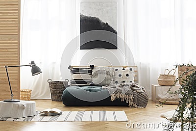 Poster above green futon with patterned pillows Stock Photo