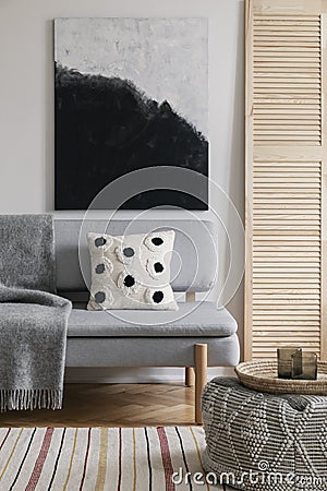 Poster above grey settee with patterned cushion in natural living room interior. Real photo Stock Photo