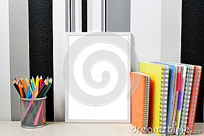Poster frame mock up template with colored notebooks and can with pencils on wooden table Stock Photo