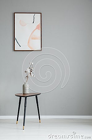 Poster on grey wall in minimal living room interior with white flowers on wooden table. Stock Photo