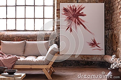 Poster next to window in industrial living room interior with grey wooden settee with blanket Stock Photo