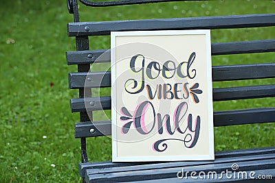 Poster with phrase Good Vibes Only on black wooden bench outdoors Stock Photo