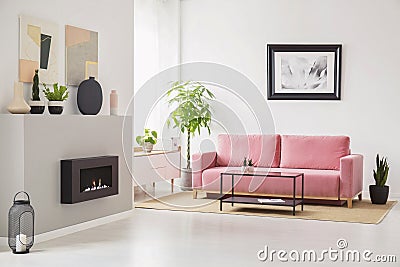 Posters on walls in Scandi sitting room interior with pink velvet couch, fresh plants, fireplace and decor Stock Photo