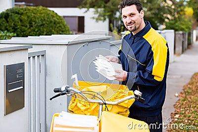 Postman delivering letters to mailbox of recipient Stock Photo