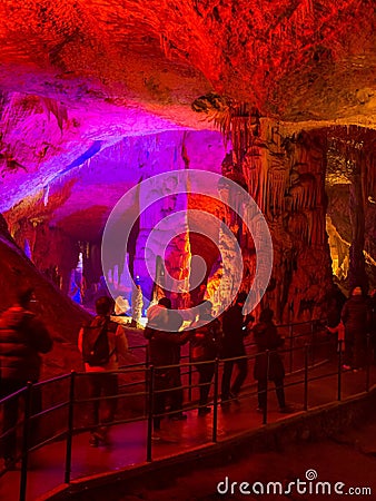 Tourists walking on path among the illuminated stalactites and stalagmites Editorial Stock Photo