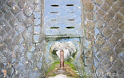 Potable fountain water in Rome with cobblestones. Stock Photo