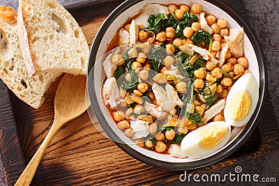 Potaje de vigilia chickpea stew with spinach and cod close-up in a bowl on the wooden tray. Horizontal top view Stock Photo