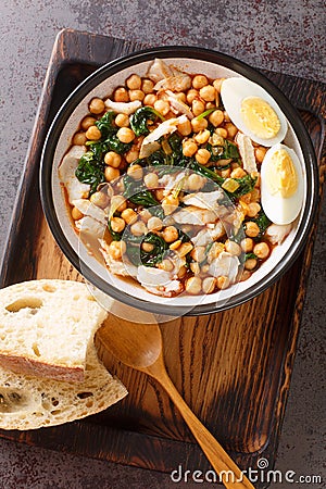 Potaje de Vigilia Spanish chickpea stew with cod and spinach close-up in a bowl on the wooden tray. Vertical top view Stock Photo